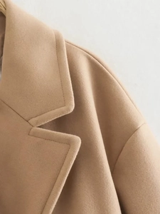 Detailed view of the lapel and shoulder stitching on a camel wool blend overcoat