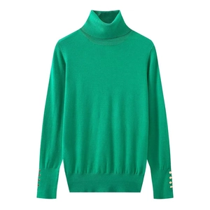 Detail of bright green turtleneck sweater with gold buttons on ribbed knit cuffs