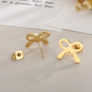 Detailed close-up of gold-plated bow earrings with mirror polish finish on beige background