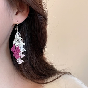 Close-up of triple-layered hollow butterfly long earrings on model with pink gradient