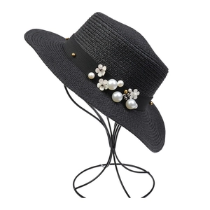 Detail of elegant black straw hat featuring white floral accents and faux pearl decor