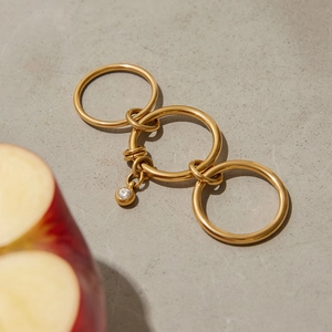 Detailed view of layered gold titanium rings with zircon charm on textured stone