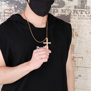 Close-up of a gold hip-hop cross pendant with inlaid crystals on a male model
