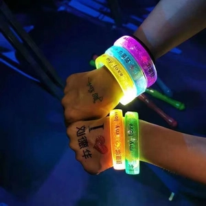 Glow-in-the-dark LED concert bracelets in multiple colors worn on wrists in the dark