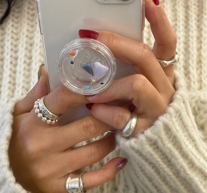 Close-up of minimalist 925 sterling silver beaded rings worn on hands with a phone grip