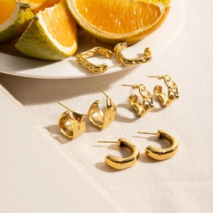 Detail of four pairs of gold C-shaped earrings with smooth and textured metal surfaces