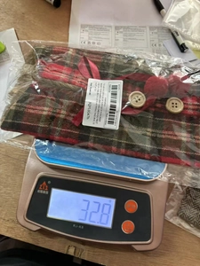Detailed view of red and black buffalo plaid wine bottle cover with fur trim on a scale