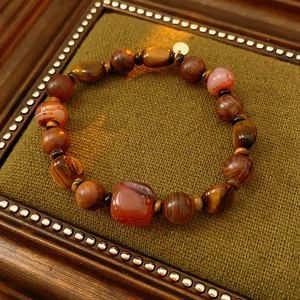 Détail macro des perles en bois d'agar, oeil de tigre et agate sur fond vintage