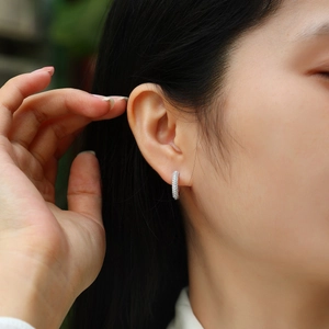 Close-up of a silver hoop earring with double-row moissanite stones on a woman's ear