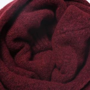 Close-up of thick wine red knitted beanie fabric showing soft wool blend texture