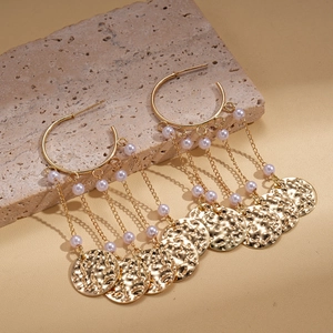 Elegant gold fringe earrings with faux pearls and textured metal discs on stone surface