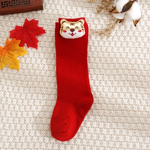 Detail view of red knitted baby socks with a cute 3D tiger character on the cuff