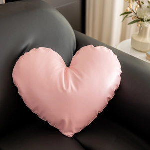 Close-up of heart-shaped pink leather pillow on a black sofa for elegant home decor