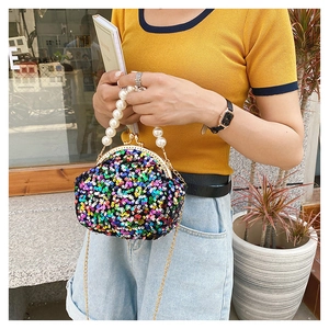 Detail shot of a sequin shell bag featuring a pearl handle and gold crossbody chain strap