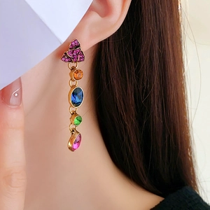 Detail of vintage French drop earrings with colorful gemstones worn by a model