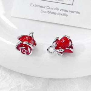 Macro shot of two red enamel rose charms with silver metal rings on a white dish
