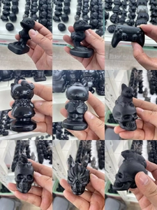 Macro shot of assorted black obsidian carvings including cute puppy and skull figurines