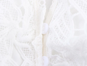 Close-up of white lace fabric texture and round buttons on the French style shirt sleeve
