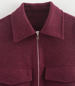 Détail d'une veste en laine bordeaux avec fermeture éclair et poches à rabat