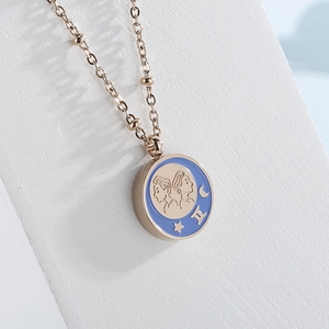 Rose gold Gemini zodiac coin necklace with blue enamel pendant on white jewelry display