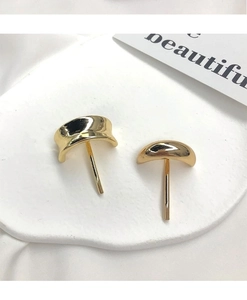 Close-up of golden geometric minimalist hair clips with polished finish on white tray