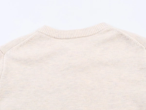 Close-up of beige knit cardigan showing ribbed crew neck and fine texture detail