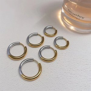 Three pairs of gold and silver two-tone hoop earrings in various sizes on white background