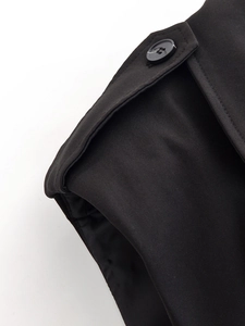 Gros plan sur l'épaulette et le bouton de la veste sans manches noire sur fond blanc