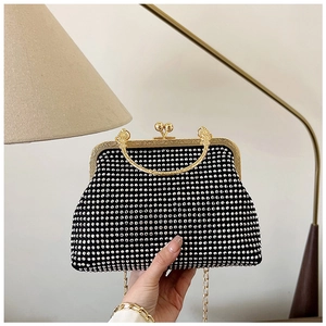 Close-up of black shell-shaped evening bag with silver rhinestones and gold ring handle