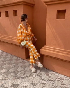 Detail of V-neck plaid crop top and ruffle hem pants in vibrant orange and white