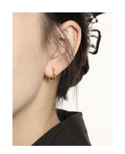 Close-up of minimalist gold circular hoop earring worn on earlobe for a stylish look