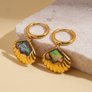 Detail of gold seashell earrings with rainbow abalone inlay on a stone pedestal