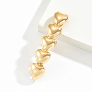 Detailed close-up of a gold metal hair clip with five linked heart shapes on a clean background