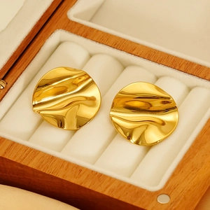 Detail shot of gold metallic wave earrings resting in a premium wooden jewelry box
