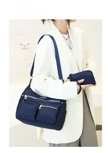 Detail of dark blue waterproof nylon shoulder bag with gold zippers and crossbody strap