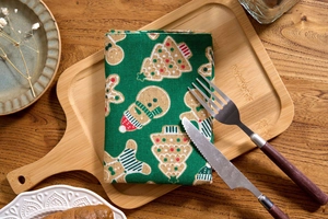 Close-up of green Christmas napkin with gingerbread man and tree prints on wooden tray