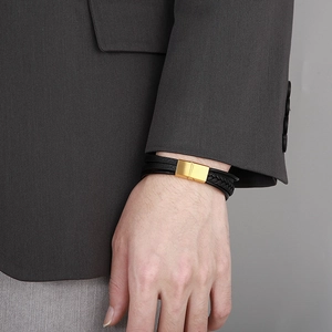 Close-up of a multi-layer black leather bracelet with a gold magnetic clasp on a wrist