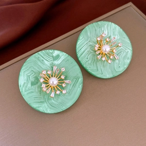 Détail de boucles d'oreilles rondes en résine verte avec fleur en perles et zircons rétro