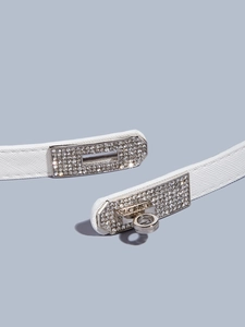 Detail of white cross-grain leather belt with silver rhinestone-encrusted turn-lock buckle