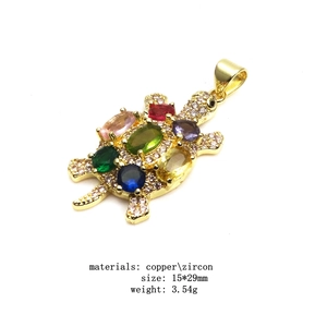 Detail view of a 15x29mm gold turtle pendant with copper zircon and colorful stones