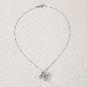 Macro shot of a silver letter M pendant with zircon stones on a fine adjustable chain