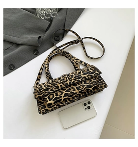 Detailed view of leopard print baguette bag with top handle and adjustable crossbody strap