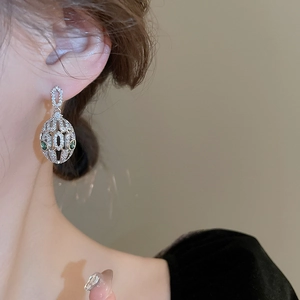 Macro detail of silver snake drop earring with green stones and pavé cubic zirconia