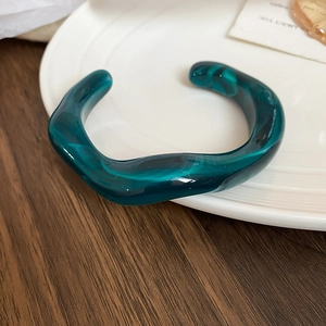 Macro detail of dark green marble pattern resin bangle on a white ceramic plate