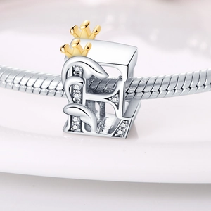 Macro view of silver letter B charm with gold crown and crystals on snake chain