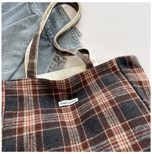 Detailed top view of plaid tote bag featuring checkered wool texture and woven label
