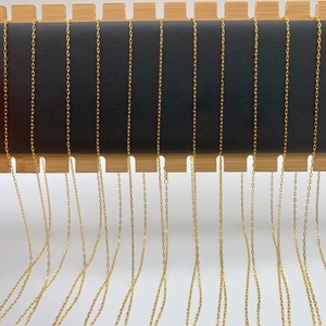 Multiple gold titanium steel lip chains hanging neatly on a professional display rack