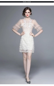 Détail de la broderie florale et des manches en tulle sur une robe beige chic