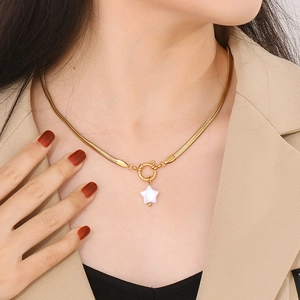 Détail d'un collier avec pendentif étoile dorée et perle porté sur un cou de femme