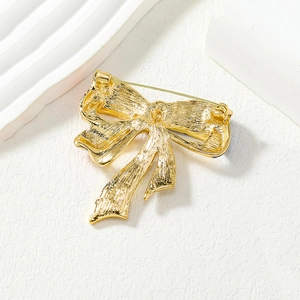 Golden American flag bow brooch back view with pin fastening on white textured surface